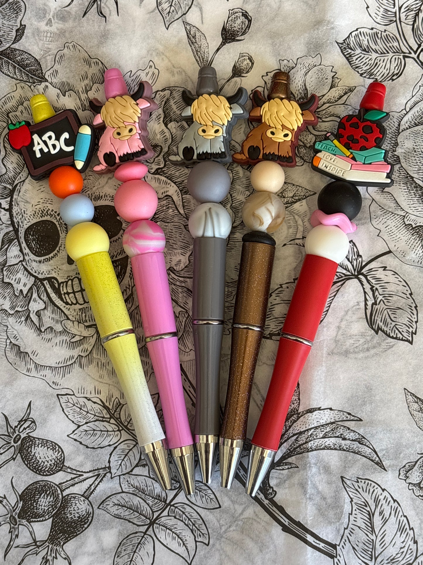 Set of colorful pens with decorative ends on a patterned background